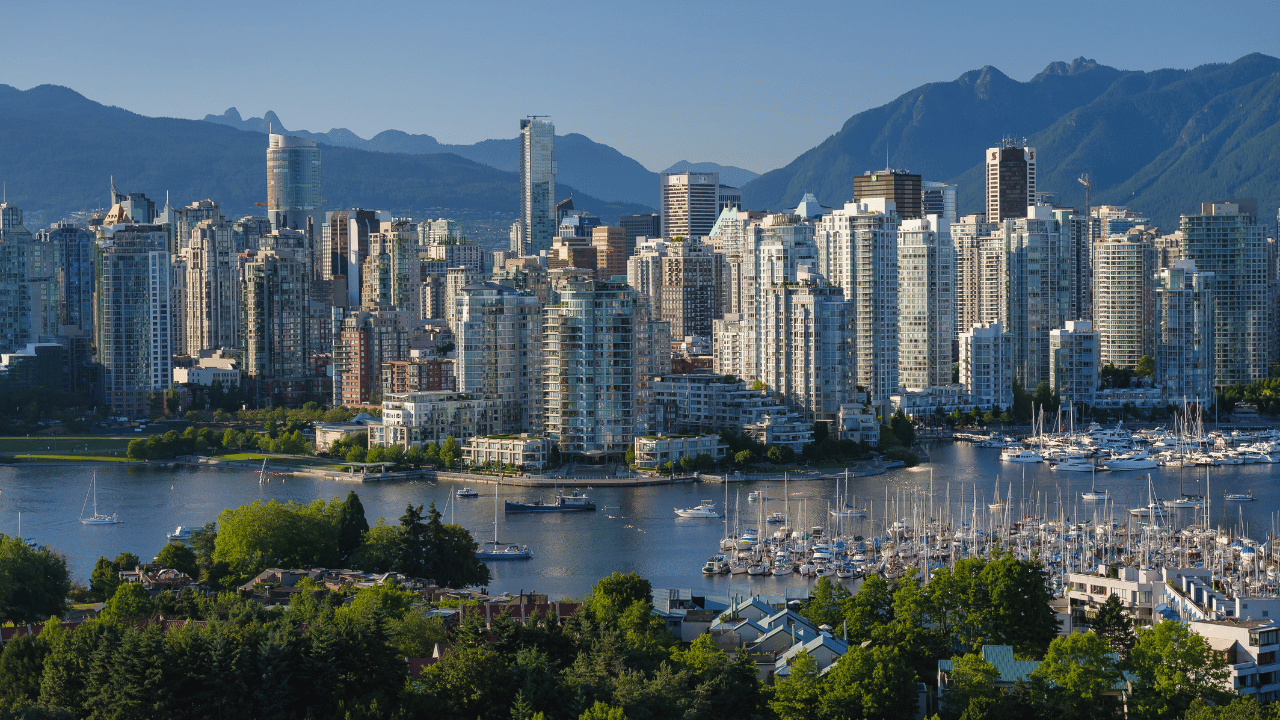 A scenic view of Vancouver including modern downtown apartment buildings, ocean and mountains